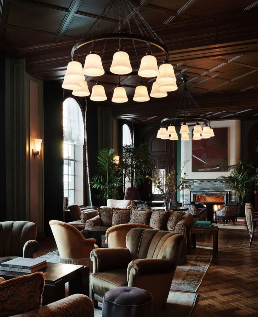 Elegant lounge area in Ned's Club Washington, featuring plush seating, a striking chandelier, and large windows with natural light.