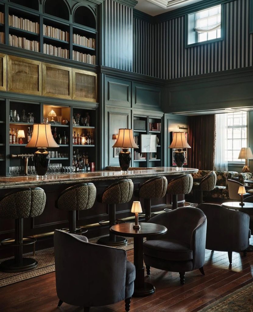 Interior view of a luxurious bar with elegant seating, dim lighting, and a well-stocked shelf behind the bar.