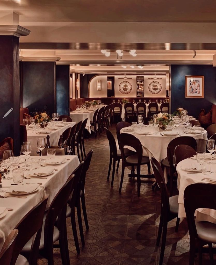 Interior of Sale e Pepe restaurant in Knightsbridge, featuring elegantly set tables with white tablecloths, dark wooden chairs, and a sophisticated atmosphere.