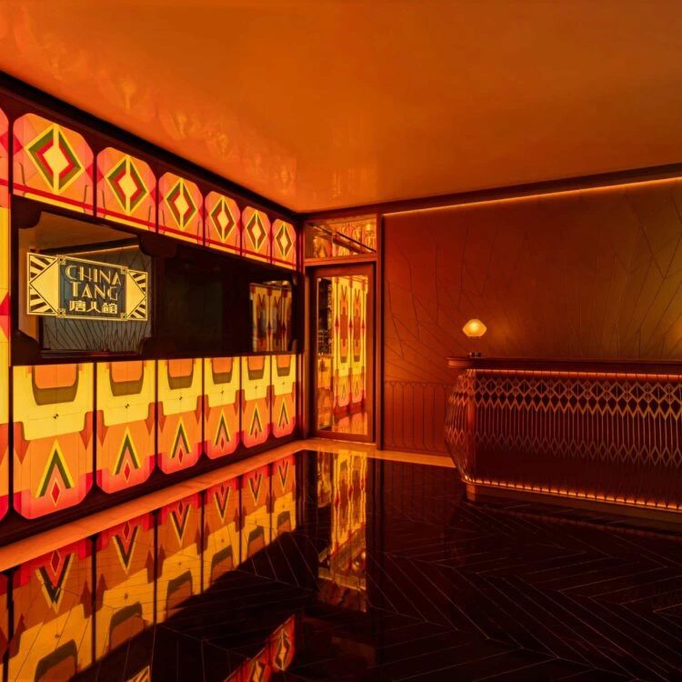 Interior view of the China Tang restaurant featuring vibrant Art Deco design elements, warm lighting, and a polished black floor.