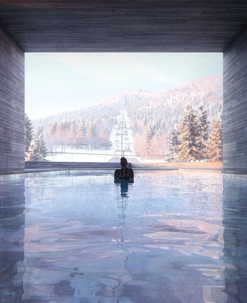 A serene view from an indoor swimming pool, featuring a person in silhouette, with a winter landscape visible through a large window.