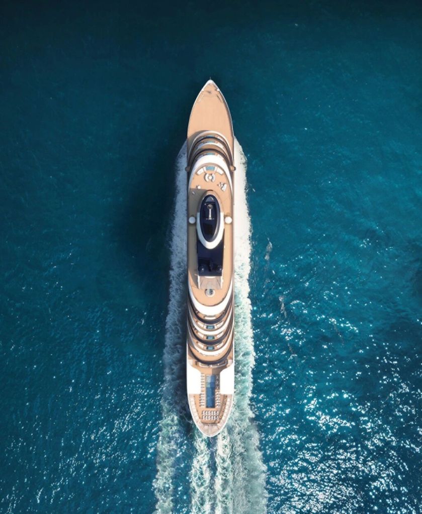Aerial view of a luxurious yacht gliding through clear blue waters.