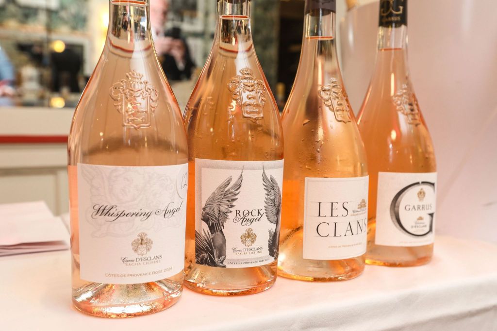 Four bottles of rosé wine displayed on a table, featuring labels from Whispering Angel, Rock Angel, Les Clans, and Garrus.