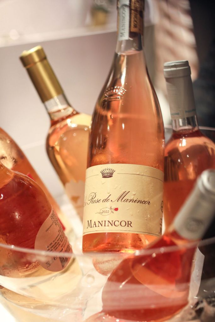 Close-up of bottles of Rosé wine, featuring a prominently displayed Manincor label. The bottles are partially submerged in ice, showcasing a selection of chilled wines suitable for a celebratory event.