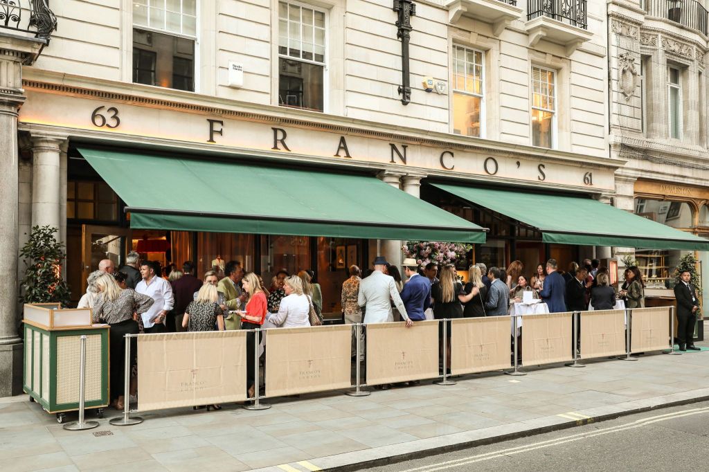 Exterior view of Franco's restaurant on Jermyn Street, featuring green awnings and guests socializing outside.