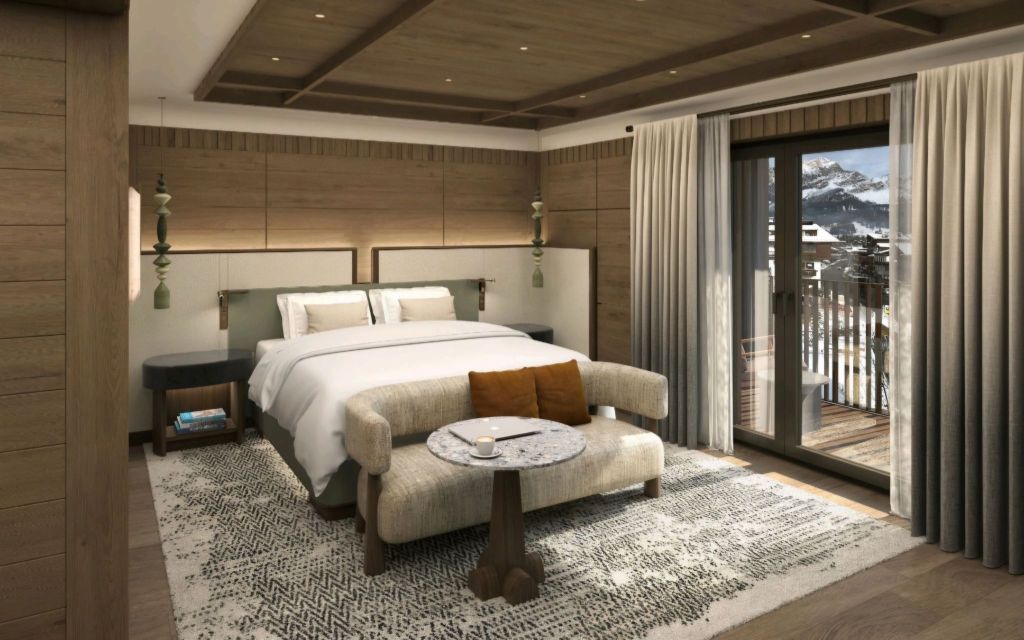 A modern hotel room featuring a large bed, stylish furniture, and warm wooden accents, with a view of mountains visible through the sliding glass doors.