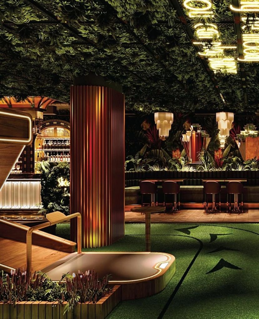 Interior view of Kapitol, featuring a stylish design with lush greenery, ambient lighting, and a bar area, showcasing a blend of modern sophistication and playful elements.