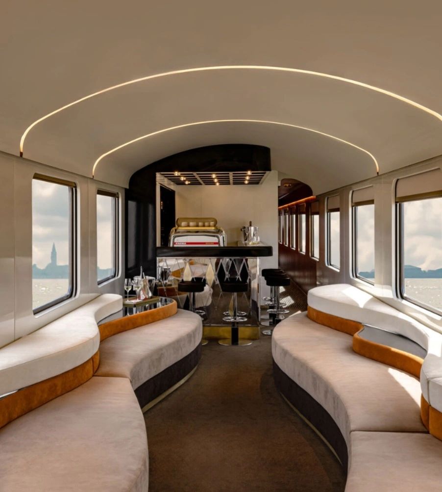 Interior view of the La Dolce Vita Orient Express showcasing luxurious seating and a stylish bar area.