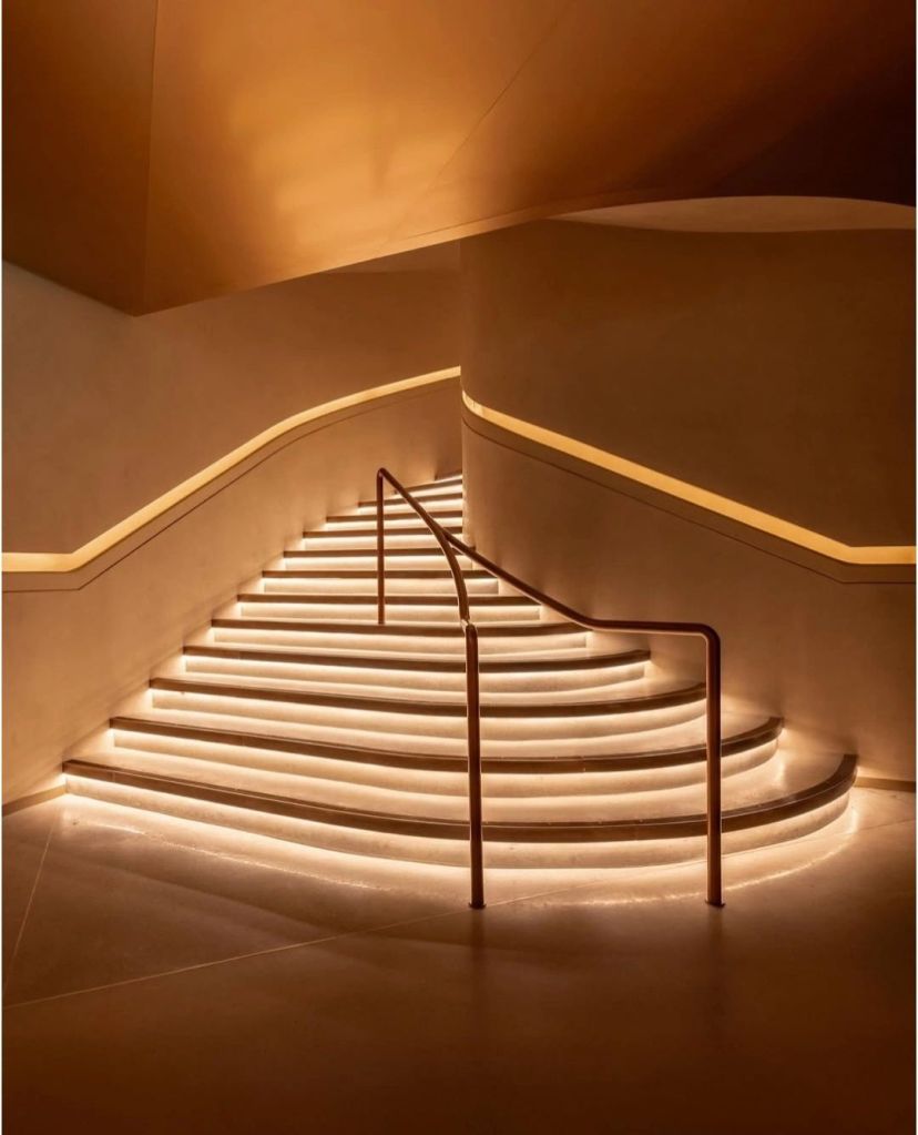 Stylish staircase with illuminated steps and a modern railing, leading to an upper level.