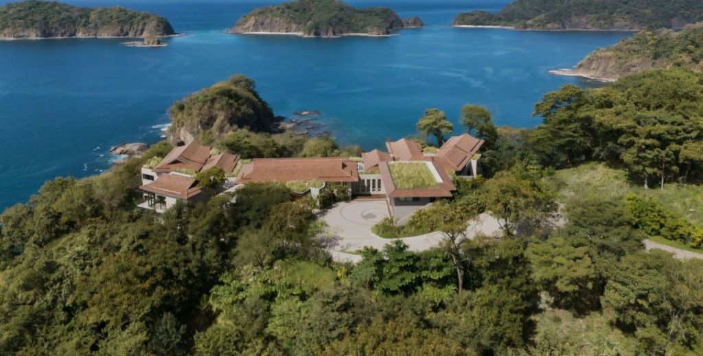 Aerial view of the Nekajui Ritz-Carlton Reserve in Costa Rica, showcasing its luxurious architecture amidst lush greenery and the Pacific Ocean.