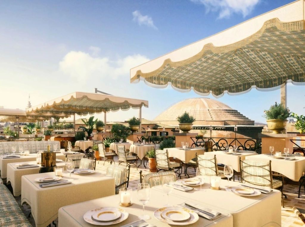 Rooftop restaurant with elegant dining tables and chairs, featuring a view of the Pantheon under blue skies in Rome.