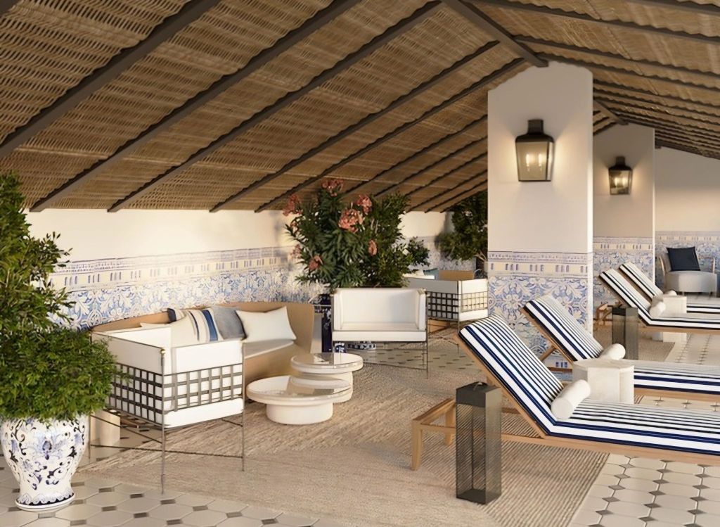 Interior view of a luxurious spa area featuring lounge chairs, decorative plants, and elegant tiled walls with blue accents, under a thatched roof.