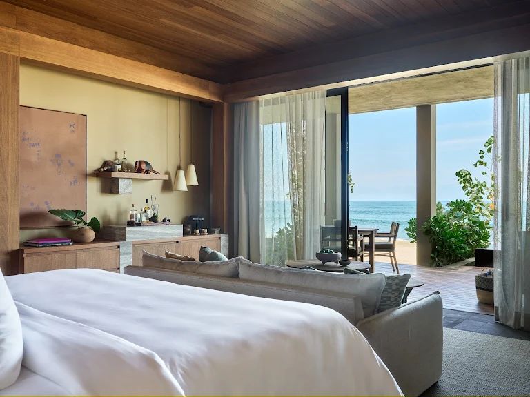 Luxurious bedroom with ocean views at Rosewood Mandarina resort, featuring modern decor and indoor plants.
