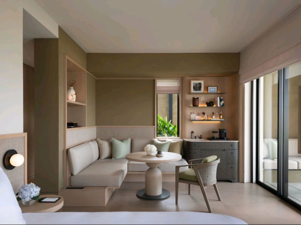 Interior view of a luxurious room at Rosewood Miyakojima, featuring contemporary decor, a seating area, and natural light entering through large glass doors.