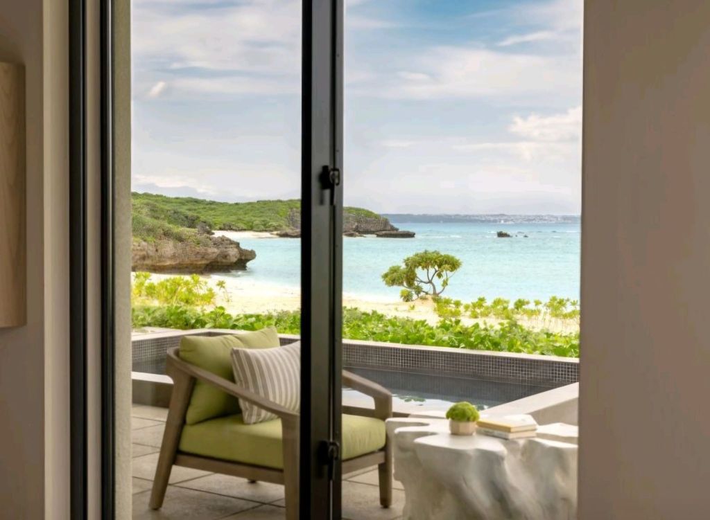 View from a luxury villa at Rosewood Miyakojima, showcasing a private patio with green seating and ocean scenery in Okinawa.
