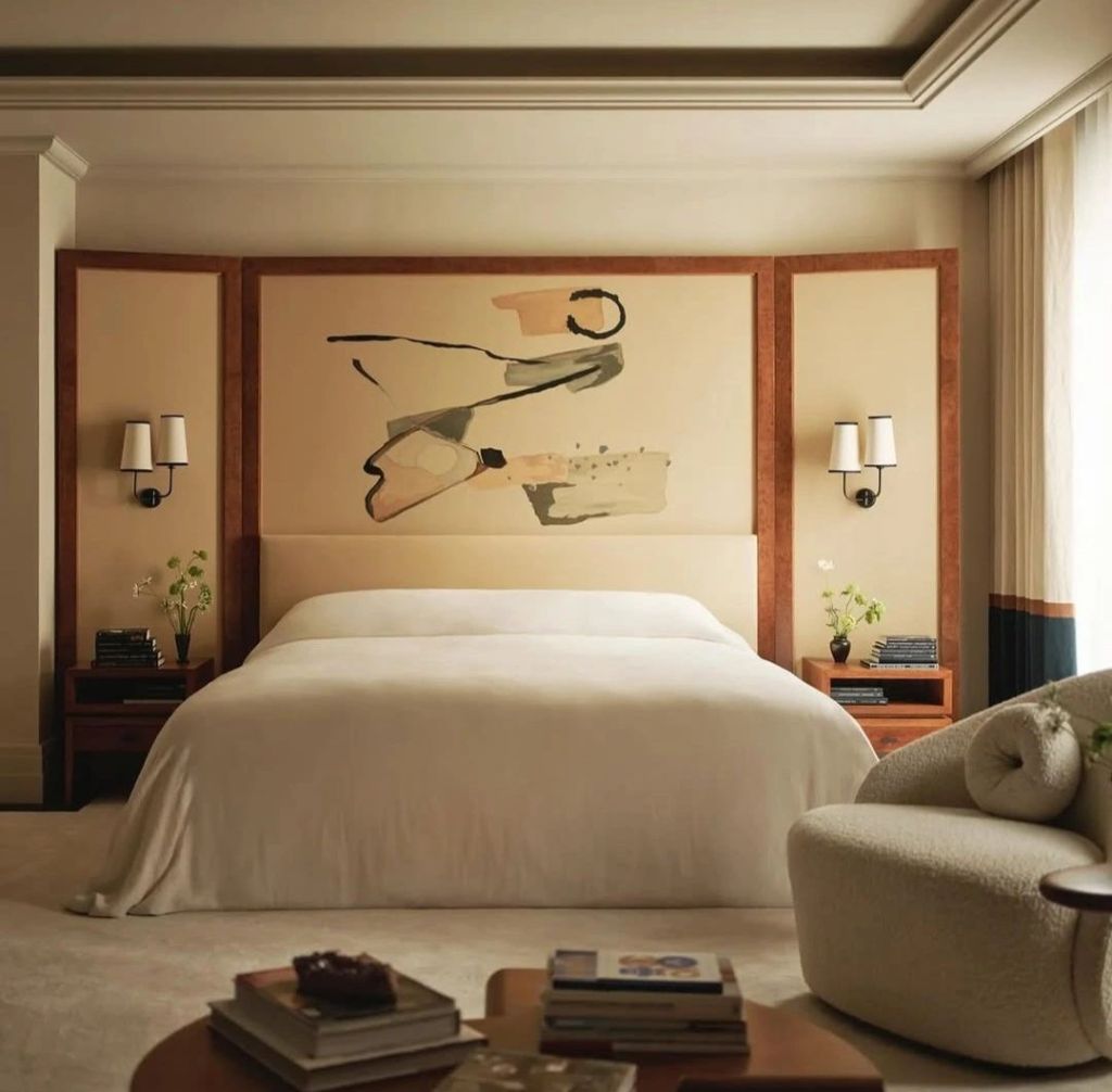 Elegant bedroom featuring a minimalist design, with a large bed and an abstract painting on the wall, complemented by bedside lamps and stylish furnishings.