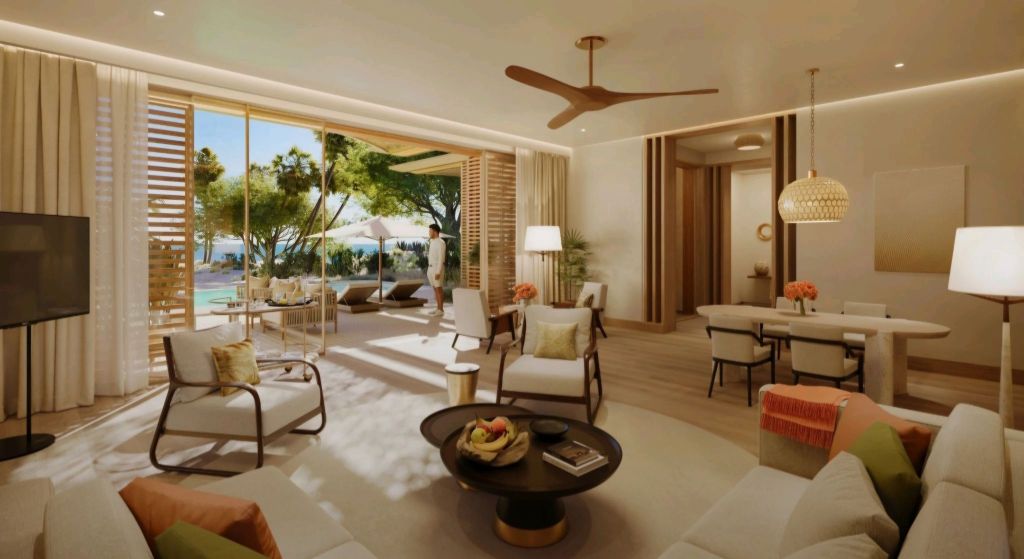 Interior view of a luxurious living room at The Red Sea Residences, featuring modern furnishings, large windows with views of greenery and outdoor lounging areas, soft lighting, and an inviting atmosphere.