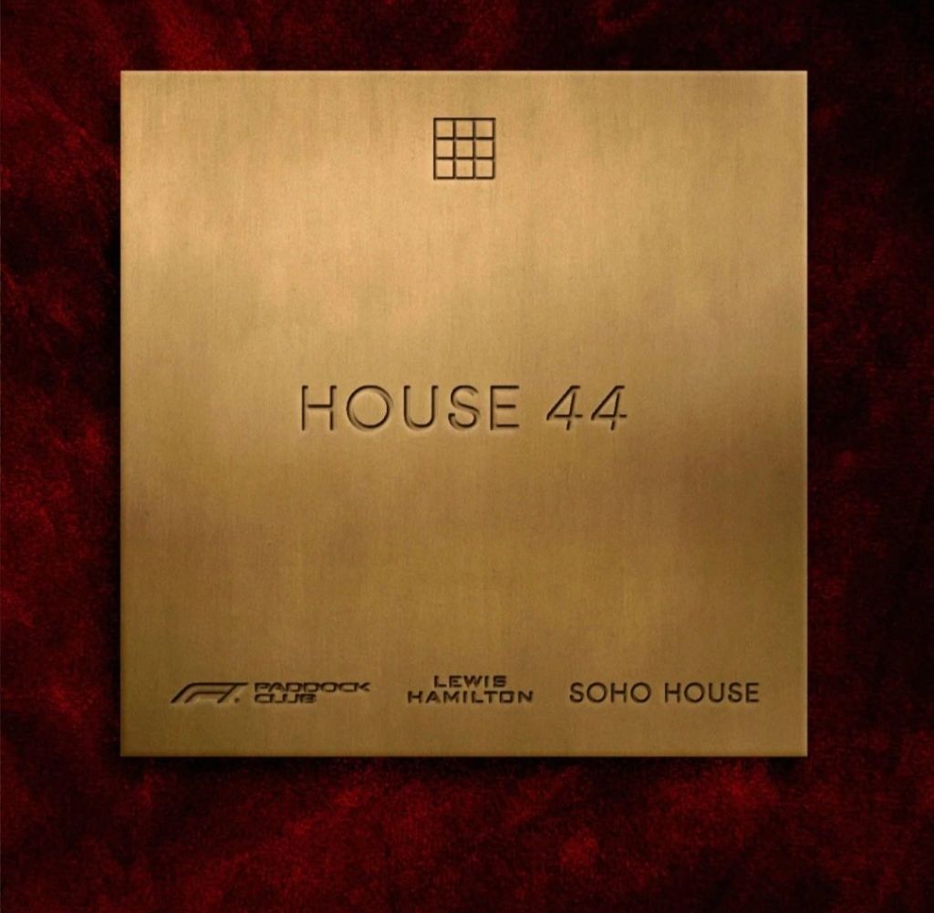 A bronze plaque displaying the text 'HOUSE 44' along with logos for F1 Paddock Club, Lewis Hamilton, and Soho House, set against a textured red background.