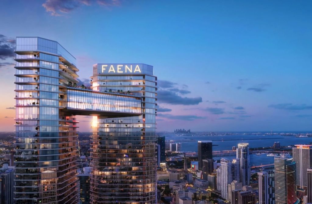 Aerial view of FAENA Residences in Miami at sunset, showcasing its modern architectural design and glass facade against a colorful sky.