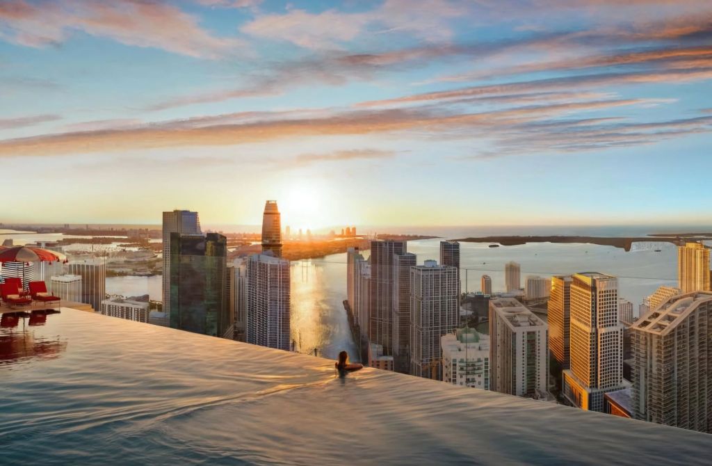 A stunning sunset view from an infinity pool atop a high-rise building in Miami, showcasing the skyline and waterfront.