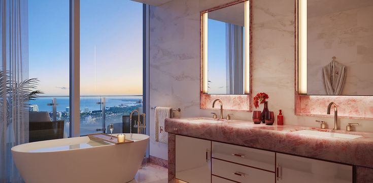 Luxurious bathroom interior featuring a freestanding bathtub, a marble countertop with dual sinks, modern mirrors, and a stunning view of Miami's skyline through large windows.