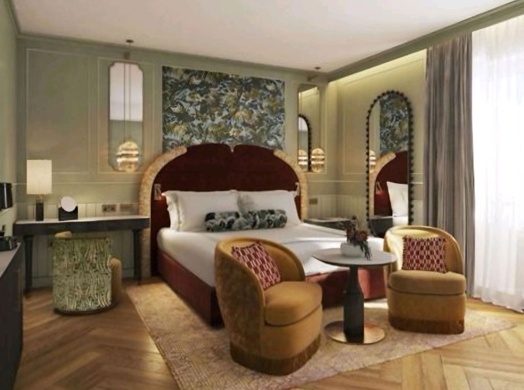 Luxurious hotel room featuring a stylish bed with decorative headboard, two elegant chairs, a small table, and artistic wallpaper.