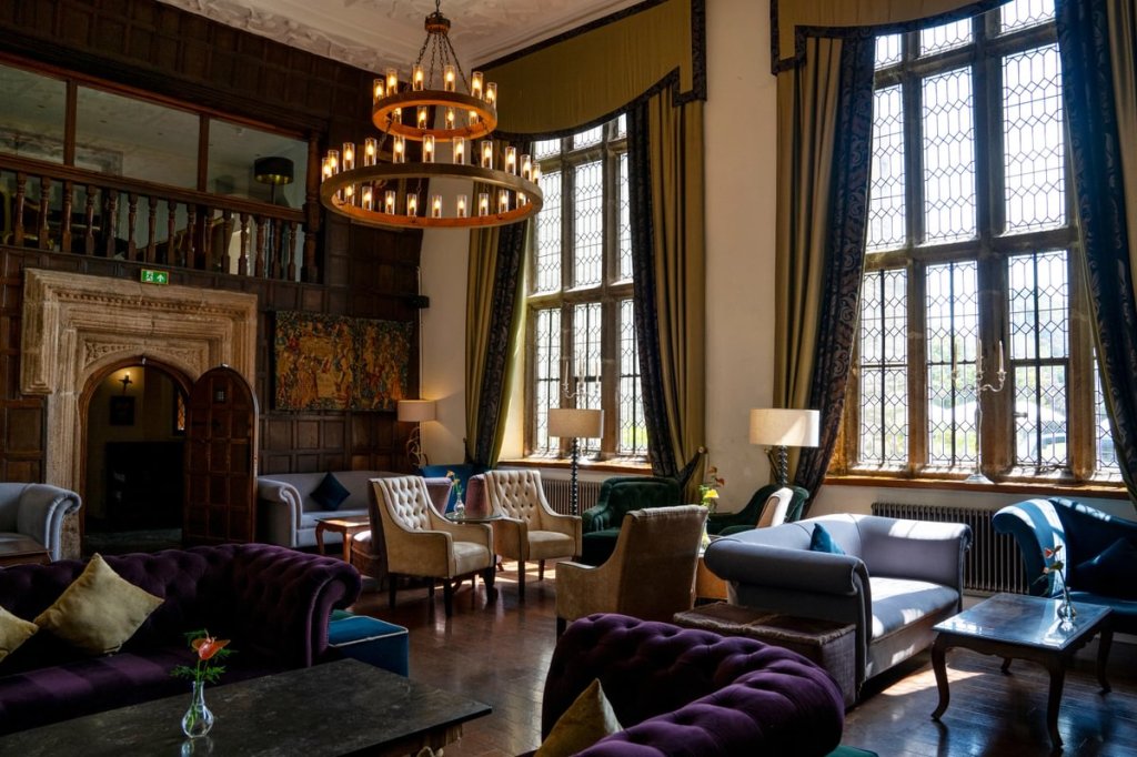 Luxurious interior of Boringdon Hall Hotel with a chandelier, comfortable seating, and large windows allowing natural light to fill the space.