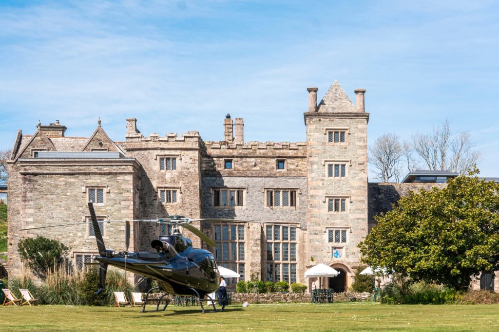 Boringdon Hall Hotel and Spa viewed from the garden, featuring a helicopter parked on the lawn in front of the historic Elizabethan manor house.