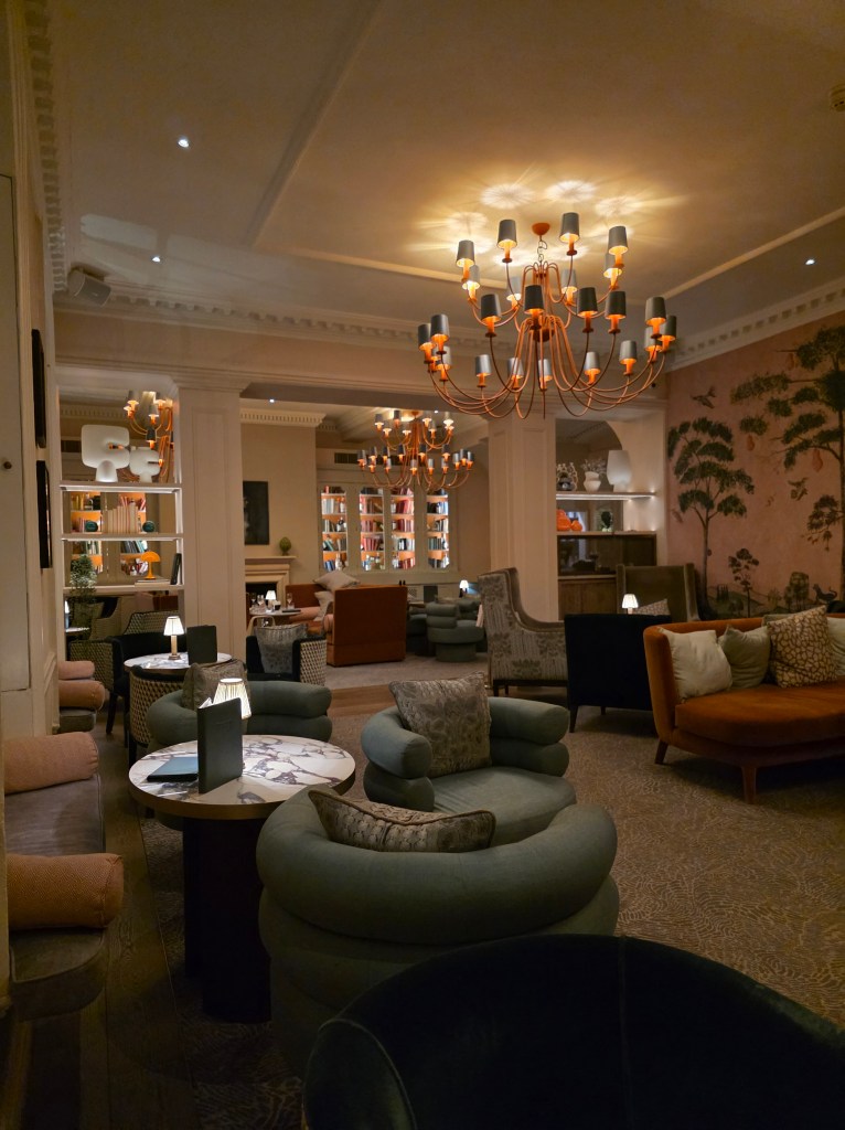 A cozy lounge area at Sopwell House featuring stylish, comfortable seating, elegant chandeliers, and warm lighting, creating a welcoming atmosphere.