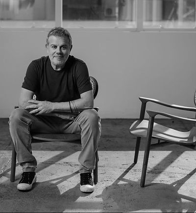 A man sitting in a modern chair inside a spacious studio, showcasing a minimalist design aesthetic.