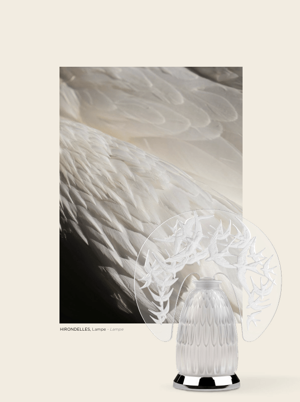 A decorative lamp featuring the Hirondelles design, showcasing a sculpted base and a translucent shade with a delicate bird motif, set against a soft, neutral background.