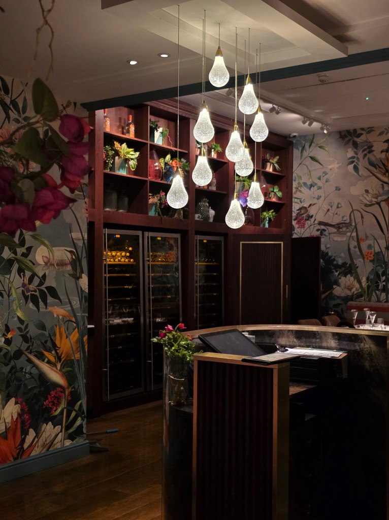 Interior view of a stylish bar area featuring elegant pendant lighting and floral wallpaper.