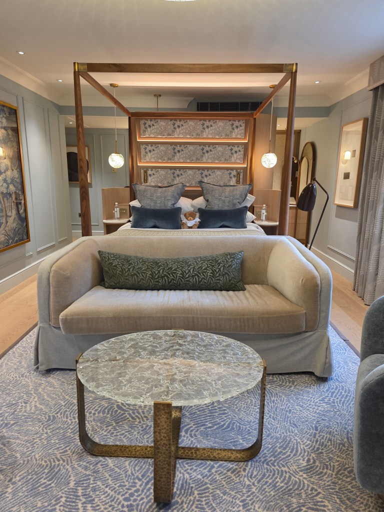 A beautifully designed hotel suite featuring a king-size bed, an elegant seating area with a plush sofa and decorative pillows, and a stylish coffee table, all set against soothing color tones and classy decor.