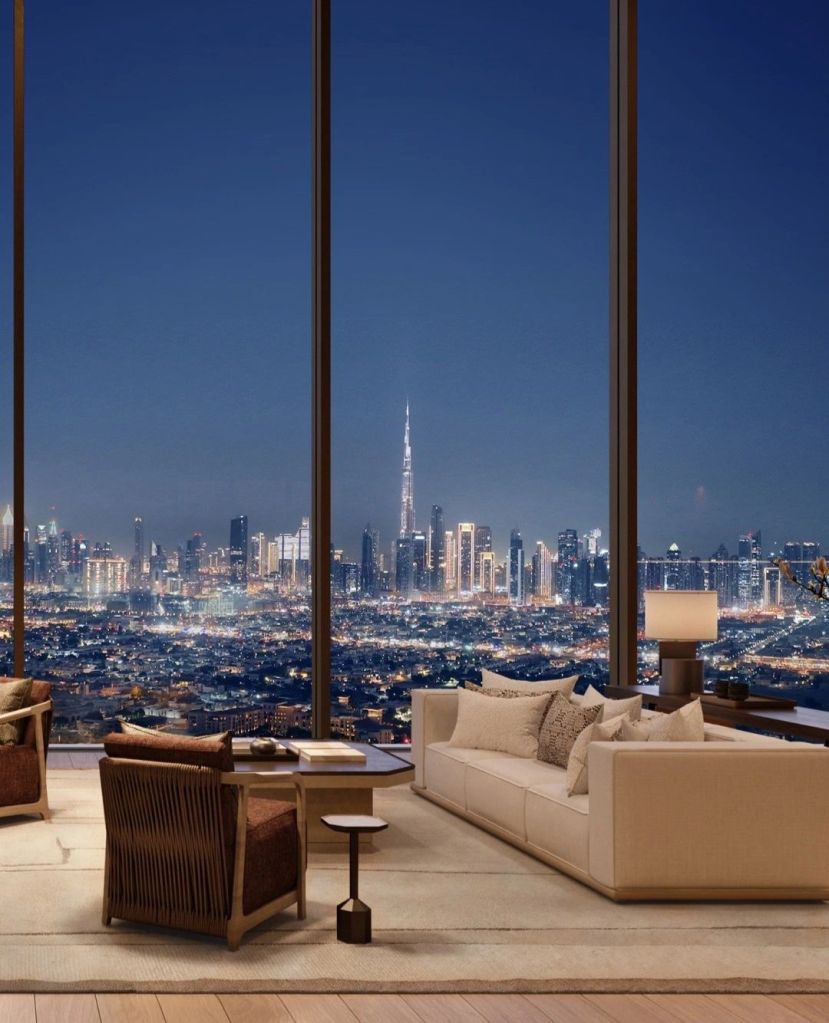 Modern living room with large windows showcasing a night view of Dubai skyline featuring the Burj Khalifa.