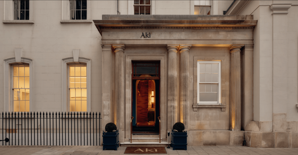 Exterior view of Aki restaurant featuring classic architecture, entrance with columns, and illuminated windows.