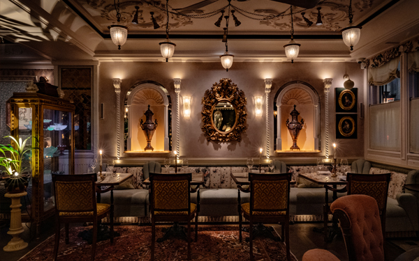 Luxurious interior of a dimly lit restaurant featuring elegant furnishings, decorative mirrors, and antique lighting fixtures.