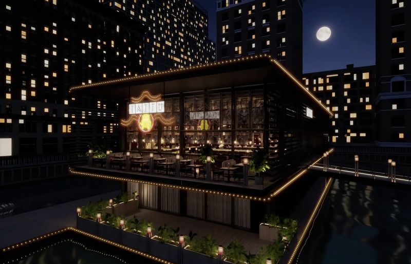 A well-lit restaurant named 'Tattu' at night, featuring large glass windows and outdoor seating, surrounded by tall buildings and a clear moon in the sky.